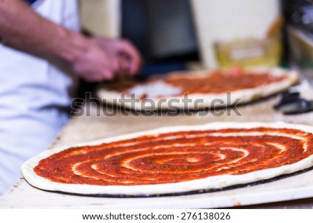 Preparing pizza with thin crust in Italian restaurant.