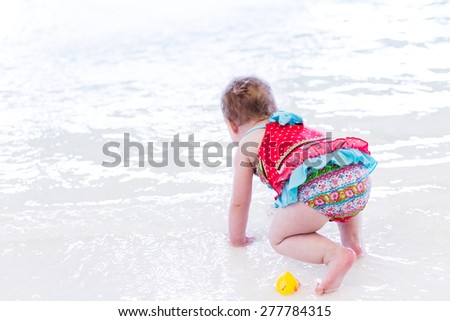 Cute toddler girl enjoying playing in the water in indoor swimming pool.