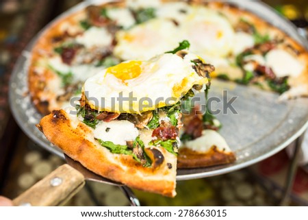 Fresh breakfast pizza with three farm fresh eggs in Italian restaurant.