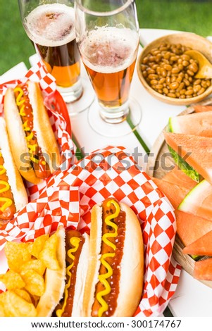 Grilled hot dogs with mustard and ketchup on the table with draft beer.