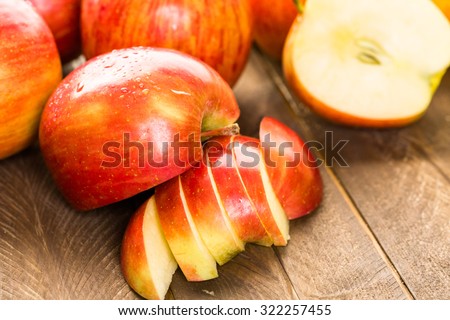 Variety of organic apples sliced on wood table.
