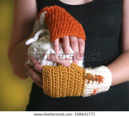 Hands wearing handmade wrist warmers and holding giant ball of yarn