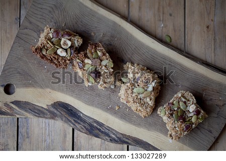 Coconut bars with pumpkin seeds and nuts on a wooden cutting board