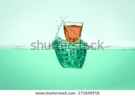 Orange vodka falling into the water making water splash