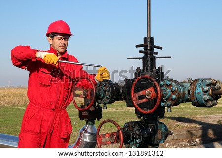 Offshore Oil Rig Operator.Oil worker in safety gear with hand tool working on oil rig equipment Offshore Oil Rig Operator.Oil worker in safety gear with hand tool working on oil rig equipment