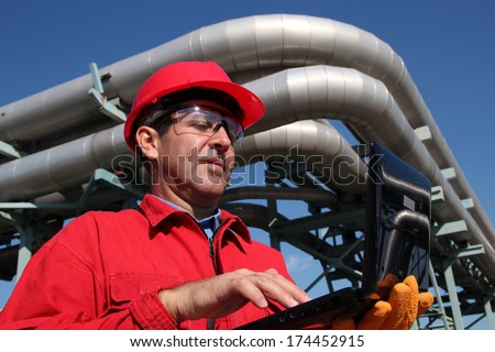 Industrial Engineer Working On A Notebook Computer Outdoor.Industrial Engineer Inside Oil And Gas Refinery Using Notebook.