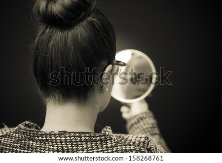 woman looking at self reflection in mirror