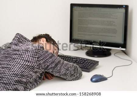 tired woman sleeping at her desk behind computer