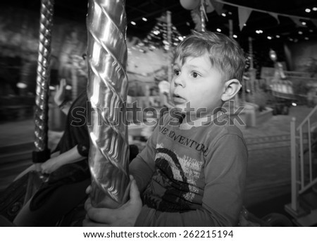 Boy in black and white with big eyes on the carousel