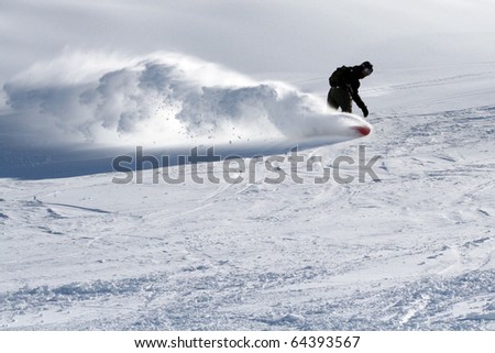 picture of snowboarder with a trail of snow in mountains