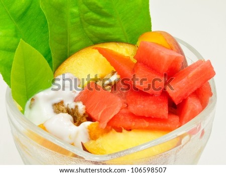 Fruit cup with watermelon, peaches, musli and green leaves