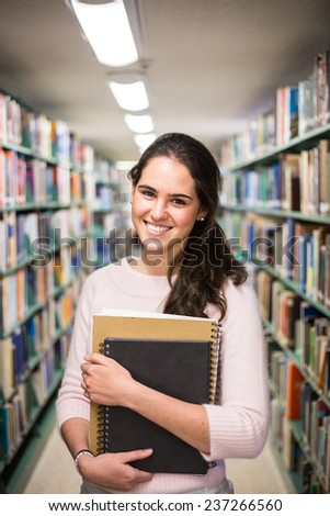 In the library - pretty female student with books working in a high school library.