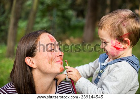 Happy mother painting her childÃ?Â´s face in the park.