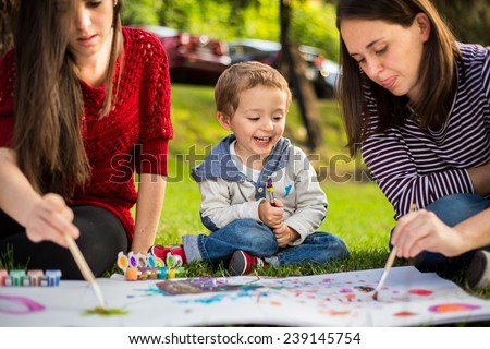 Happy Mother aunt sister and son child painting in the park.
