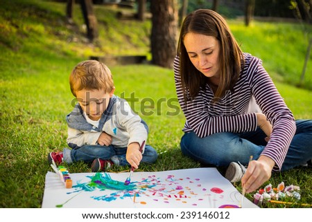 Happy Mother and son child painting in the park.
