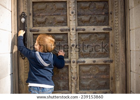 Cute little boy baby knocking on old door.