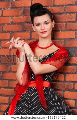 Girl in vintage dress near brick wall. Portrait of stylish woman in a vintage dress with makeup.