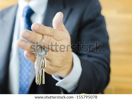 Businessman with house key in hand, using depth of field focus