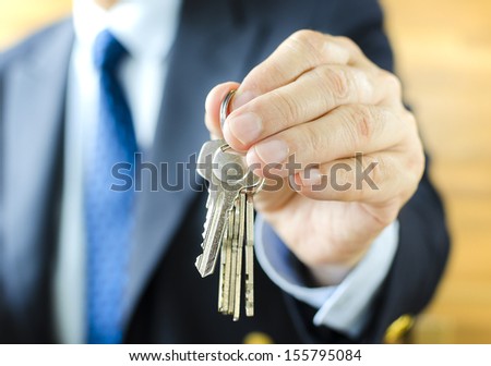 Businessman with house key in hand, using depth of field focus