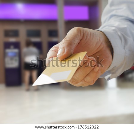 Hand show credit card with ATM machines as a backdrop