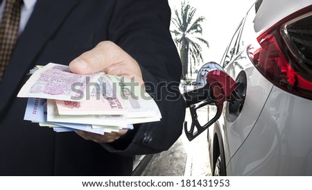 Businessman paying cash for car refuel