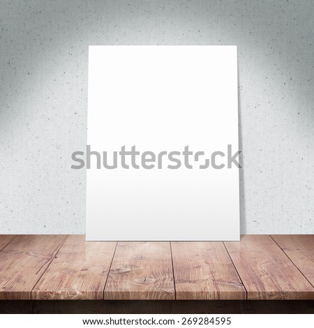 The white poster on a wooden table with Fabric texture background