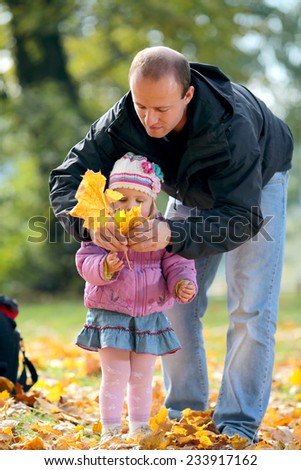Man with a daughter collect fallen list in Park