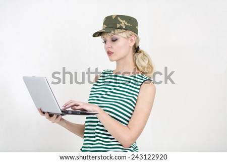 The military person standing types the text on the laptop.