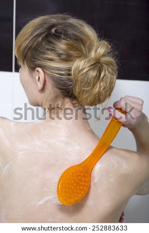 Woman looks after herself, washes to itself a back in a bathroom