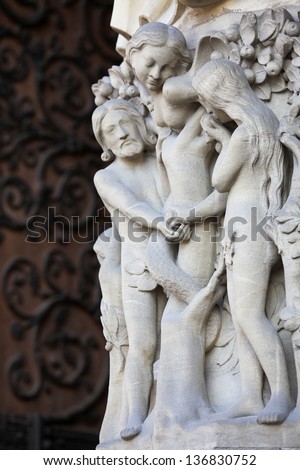 Adam and Eve eat the Forbidden Fruit at the Tree of Life in Paradise, sculpted at the Notre Dame Cathedral in Paris, France.