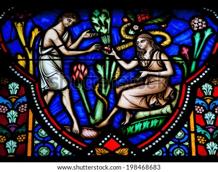 BRUSSELS, BELGIUM - JULY 26, 2012: Adam and Eve eating the Forbidden Fruit in the Garden of Eden on a stained glass window in the cathedral of Brussels.