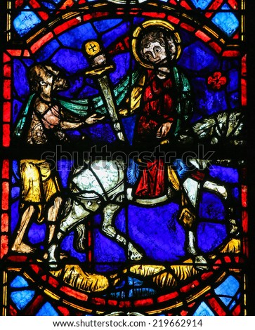 TOURS, FRANCE - AUGUST 8, 2014: Stained glass window depicting Saint Martin of Tours cuting a piece of his cloak in the Cathedral of Tours, France.