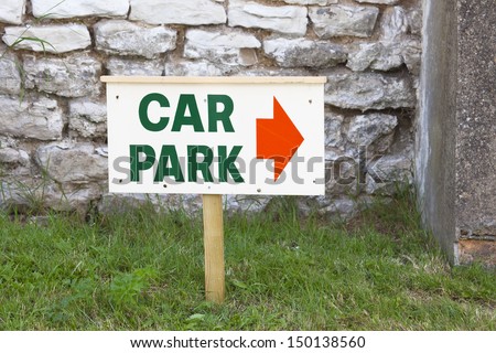 Temporary car park sign  with red arrow direction indicator on wooden post stuck in the ground