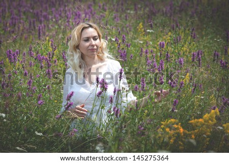Beautiful young woman in a field of flowers, smiling and having a positive attitude