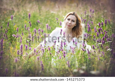 Beautiful young woman in a field of flowers, smiling and having a positive attitude