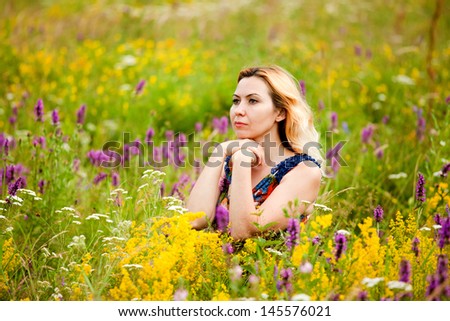 Beautiful young woman in a field of flowers, smiling, feeling positive and peaceful