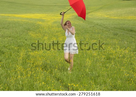 Woman with red umbrella in a green field