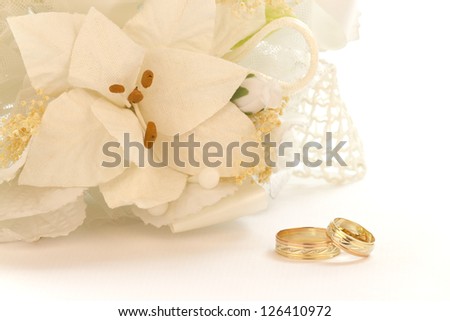 Bouquet of white flowers with wedding rings on a white background.