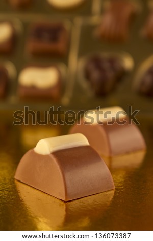 Close up of two bonbons with a box of chocolates.