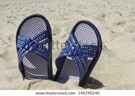 Picture of flip flops on beach sand in a hot summer day.