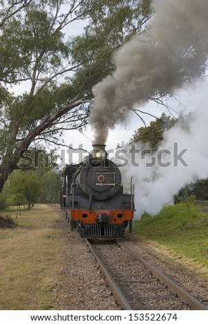 Steam train traveling along the railway line with steam bellowing out the sides and the top