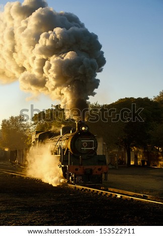 Steam train pulling out of the yard early morning in winter just as the sun is starting to rise
