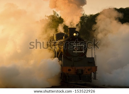 Steam train pulling out of the yard early morning in winter just as the sun is starting to rise
