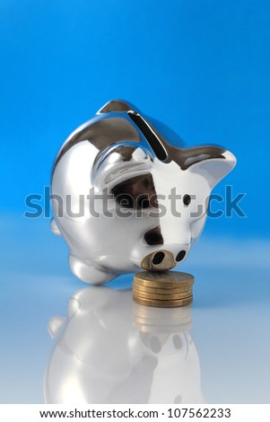 pig bank sniffing coins on blue background
