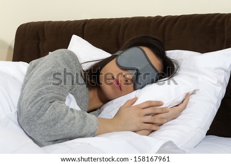 Young woman lies with sleeping mask in the bed -Taking a nap with  sleeping mask.