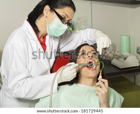 Young woman with open mouth during drilling treatment at the dentist.