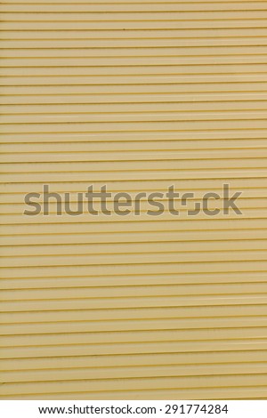 Background under the corrugated metal painted in yellow color with horizontal stripes