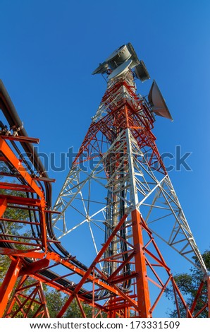 Telecommunications tower, painted white and red in a day of clear blue sky.