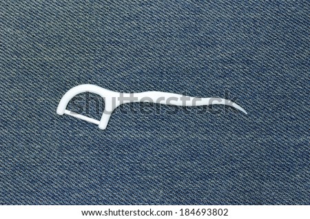 Floss toothpick white. Placed on the surface of denim fabric.