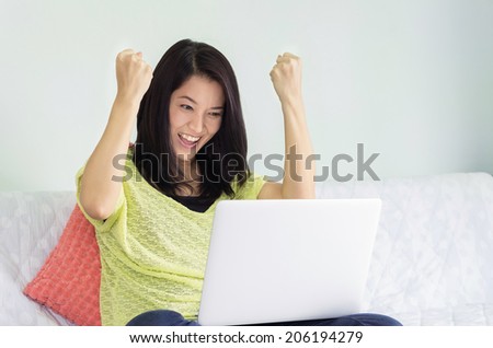 Beautiful and happy asian woman with a laptop indoor.